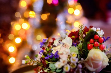 Parlak ışıkları olan çiçeklerdeki yüzükler. Yüzükler, romantik bir ortam için renkli ışıklarla aydınlatılmış canlı bir çiçek buketinin üzerinde duruyor..