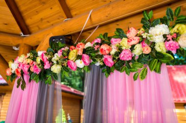 Pembe örtülü çiçek dekoru. Renkli çiçeklerden oluşan güzel bir düzenleme. Bir etkinlik için dekore edilmiş rahat bir mekanda yumuşak pembe perdeler..