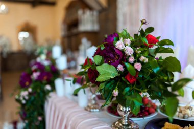 Chic floral design elevates decor. Colorful flowers in silver vases make a stunning centerpiece for a festive celebration in a decorated venue. clipart