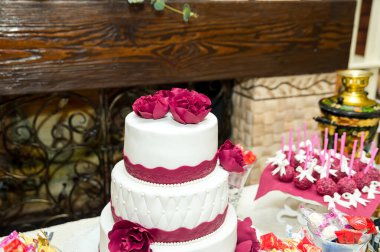 Gül süslemeli düğün pastası. Üç katlı düğün pastası gösterileri karmaşık detaylar ve güzel gül süslemeleri, şenlik masasında sergileniyor..