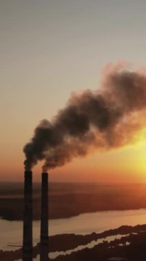 Fabrika gün batımında çevreyi kirletir. Toksik girişim bacaları akşam gökyüzüne karşı tüp oluşturarak siyah duman salıyor. Doğada zararlı üretim boruları tüttürmek. Dikey video