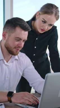 Ofiste çalışan genç iş adamları. Yakışıklı iş adamı ofiste profesyonel bayan danışmanı dinler. Güzel bir iş kadını ve erkek bilgisayarda veri tartışıyor. Dikey video