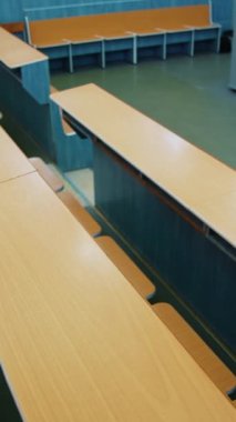 Öğrenciler için boş oditoryum. Üniversitede tahta masalar ve sandalyeler. Salgın sırasında sınıfta kimse yoktu. Dikey video