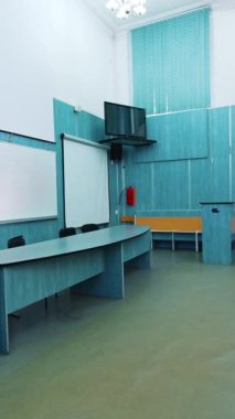 Konferans salonunun modern iç mimarisi. Üniversite sınıfında beyaz kurul ve başkanlık masası. Yeni ekipmanlarla boş oditoryum. Dikey video