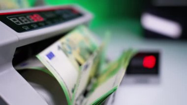 Euro banknotları nakit sayma makinesinde döndürüldü ve sayıldı. Sayı ekranda hızla yükseliyor. Kapatın. Bulanık arkaplan.