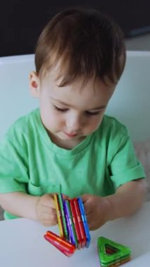 Küçük çocuk farklı geometrik şekilli oyuncaklarla oynuyor. Sevimli çocuk oyun oynarken konuşuyor. Üst Manzara. Dikey video