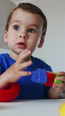 Bebek oyuncaklarla oynayarak renkleri ve şekilleri öğreniyor. Bebek oyun boyunca ders çalışıyor. Düşük açı. Dikey video