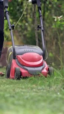 Bahçıvan çimen biçiyor. Çim biçme makinesiyle kesilmiş ev bahçesi çimenleri