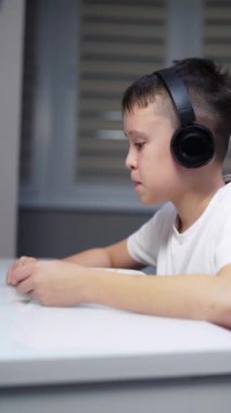 Tabletli şirin bir çocuk. Çocuk tablete bakıyor ve mutfakta yemek yiyor.