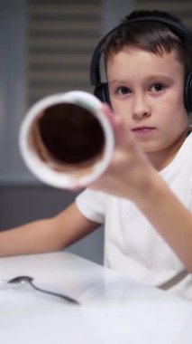 Çocuk yemek yiyor ve tablet seyrediyor. Çocuk tatlı yiyor ve tablet ekranına bakıyor.