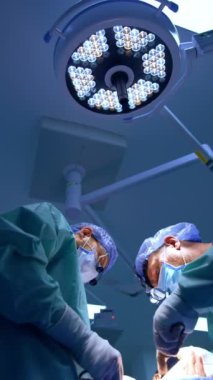 Kafkas cerrahları operasyonda işbirliği yapıyorlar. Doktorlar modern tıbbi aletler kullanır. Düşük açı. Dikey video.