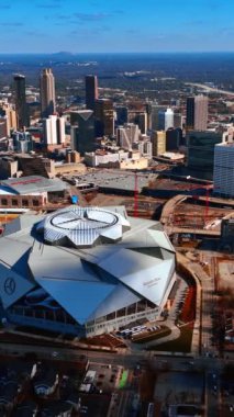 Atlanta şehir merkezindeki Mercedes-Benz Stadyumu 'nun alışılmadık binası. Güneşli bir günde şehir panoraması. Dikey video