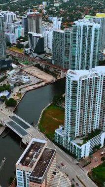 Miami, Florida, ABD 'nin çeşitli şehirlerinin üzerinde uçuyorlar. Yüksek binaların ve alçak binaların arka planda inşa edildiği İHA görüntüleri. Dikey video