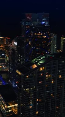 İnsansız hava aracı gece vakti muhteşem gökdelenlerin etrafında uçuyor. Miami, Florida, ABD 'nin muhteşem manzarası. Dikey video