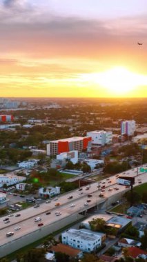 Uçak Miami, Florida, ABD panoramasının üstündeki renkli gökyüzünde uçuyor. Yukarıdan güzel bir gün batımı. Dikey video