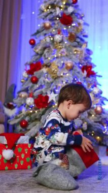 İki yaşındaki çocuk Noel çorabını aldı ve renkli boncuklar yere düştü. Tatiller evde kutlanır. Dikey video