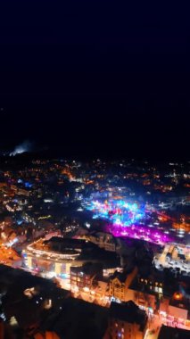 Polonya 'nın Zakopane şehrinin güzel dekore edilmiş merkezinde festival ışıkları açık. Kasabanın gece manzarası yukarıdan görünüyor. Dikey video.