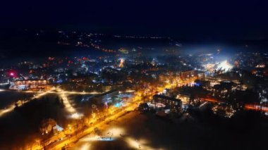 Yumuşak sarı ışıkla aydınlatılan bulvar sıcacık kasabayı geçiyor. Polonya, Zakopane 'de kışın gece manzarası. Hava görünümü.