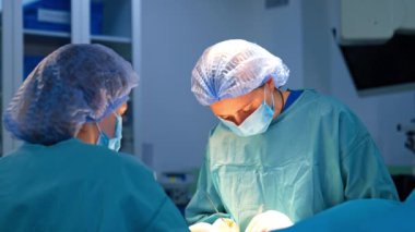 Kadın cerrah ve ameliyathane hemşiresi tarafından ameliyat edildi. Doktor iş yerinde metal aletler kullanıyor..