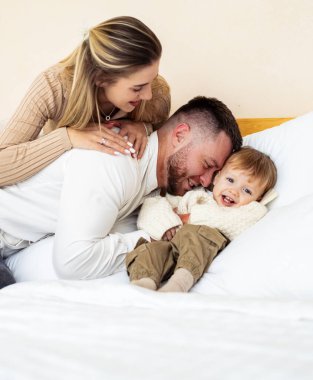 Sıcak uzayda aile eğlencesi. Neşeli bir aile, güneşli bir günde, rahat bir yatakta oynarken kahkahalarını paylaşır..