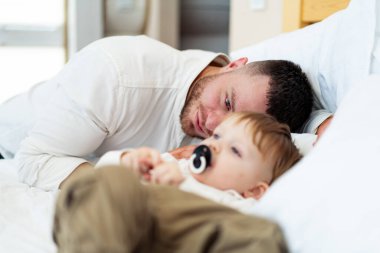 Babam küçük bebekle rahat bir odada oynuyor. Bir baba, yürümeye başlayan çocuğuyla rahat bir yatak odasında vakit geçirmekten zevk alır ve birlikte bir bağ kurma deneyimi yaratır..