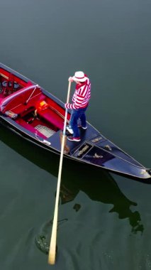 Gondolcu, gondolu nehre atıyor. Gondolcuların hava görüntüsü turistleri gondolda taşıyor