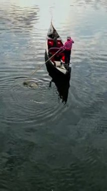 Şehirde gondolla yürü. Gondol nehre iniyor. İnsanları gemiye taşıyor.