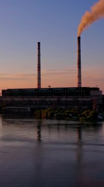 Nehir kenarındaki sanayi havadan görünüyor. Gün batımında nehrin yakınındaki fabrikanın hava aracı görüntüsü