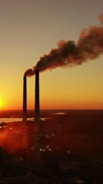 İnsansız hava aracından sanayi manzarası. Fabrika bacası gün batımında hava kirliliğine duman pompalıyor.