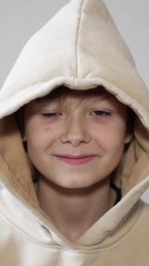 Kameraya gülümseyen zeki, yakışıklı bir genç çocuk. Kapüşonlu siyah saçlı adam, yakın plan portre. Dikey video