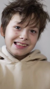 Komik genç eğleniyor, surat asıyor, kameranın önünde maskaralık yapıyor. Dilini gösteren çocuk. Kapatın. Dikey video