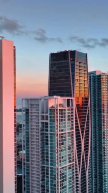 Güneşin batışının ışığını yansıtan muhteşem bir gökdelen. Miami şehir merkezinin muhteşem manzarası tepeden. Dikey video