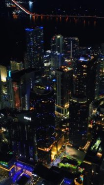 Miami, Florida, ABD 'nin muhteşem şehir merkezinden yükseliyor. İnsansız hava aracı görüntüleri gece metropolün üzerinde. Dikey video