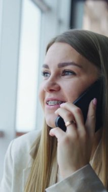 Bayan ofis çalışanına telefon var. Akıllı telefonla çalışan güzel bir iş kadını. Dikey video