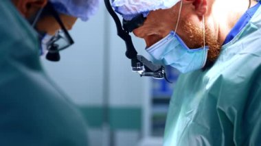 Operasyondaki iki erkek cerrahın işbirliği. Doktorlar hastalara bakmak için yüz yüze gelirler. Kapat..