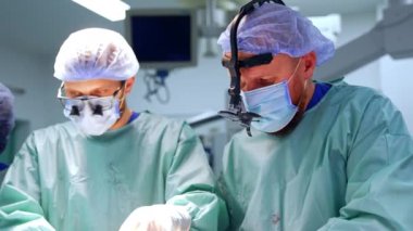 Cerrahlar ameliyat masasının yanında yan yana durur. Doktor, kesiği kapatmak için bandaj al..