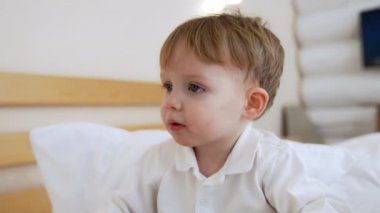 Beyaz tişörtlü güzel beyaz erkek bebek koca kafanın üstünde oturuyor. Evde sakin ve huzurlu bir çocuğun portresi. Kapat..