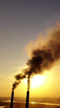 Gün batımında hava kirliliği. Kirli dumanlı endüstriyel borular atmosferi kirletiyor. Akşamları zehirli dumanlı iki büyük boru. Dikey video