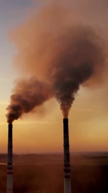 Çevre kirliliği. Güzel bir günbatımında fabrikanın endüstriyel borularından zehirli duman çıkıyor. Ekolojik felaket. Dikey video