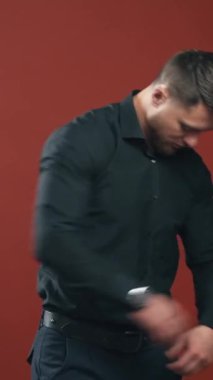 Siyah gömlekli güçlü vücutlu yakışıklı adam kameraya bakıp hazırlanıyor. Yarım bellik görüntü videosu. Dikey video
