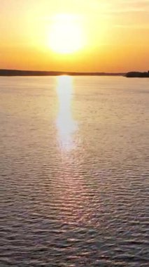 Güzel gün batımı nehire yansıyor. Günbatımı göl manzarası. Renkli gökyüzü. Dikey video