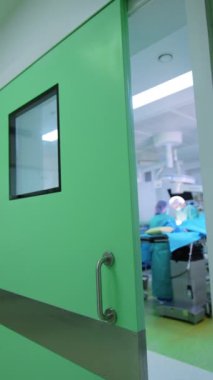 Modern hastanede bir ameliyathanenin kapısını açtı. Cerrahi operasyon odanın içinde gerçekleşiyor. Dikey video.