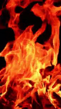 Ateş kırmızı alevle parlıyor. Sıcak şömine turuncu yanıklarla parlıyor. Dikey video