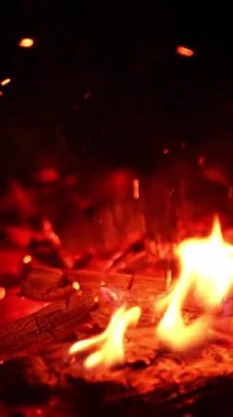 Yakacak odunda kırmızı bir alev. Yanan kütükler görüntüyü kapatır. Dikey video