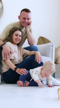Küçük şirin bir bebekle evde oynayan bir aile. Ebeveynlik yaşam tarzı. Dikey video