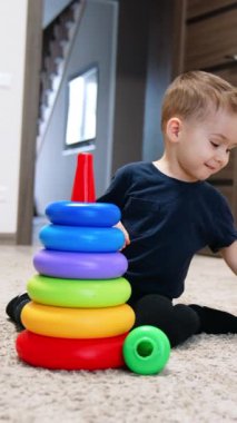 Yerde oynayan renkli bir oyuncak. Oyuncaklarla çocukluk eğitimi aktivitesi. Dikey video