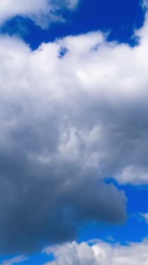 Kabarık bulutların hareket zamanı. Üzerinde bulutlar akan mavi gökyüzü. Dikey video