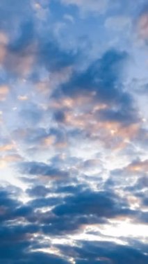 Bulutlarla kaplı mavi bir gökyüzü. Akan güneş ışığı manzaralı gökyüzü. Dikey video