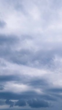 Gökyüzünde kayan yüksek bulutlar. Mavi arka plan rüzgarı akıyor. Dikey video