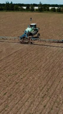 Tarlaların pestecide ile tedavi edilmesi. Alanda böcek ilacı püskürten traktörün hava görüntüsü